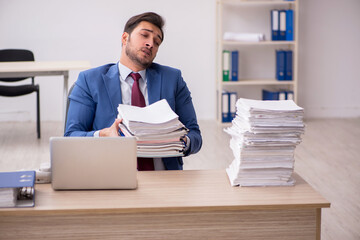 Young male employee and too much work in the office