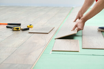 Carpenter installing laminate flooring in room