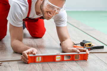 Carpenter taking measurements of laminate flooring in room