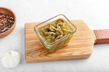 Glass bowl with canned jalapeno on light background
