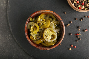 Bowl with canned jalapeno on dark background