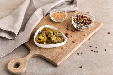 Bowl with canned jalapeno and spices on light background