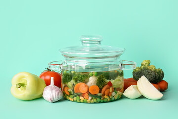 Stylish cooking pot with tasty soup and ingredients on color background