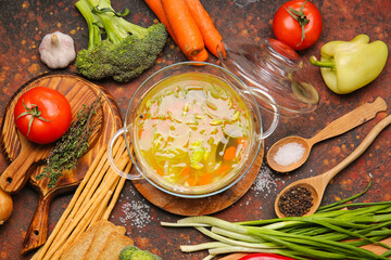 Stylish cooking pot with tasty soup and ingredients on grunge background