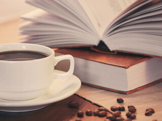 The concept of teaching education with the opening of a book or textbook in the library. a cup of fresh coffee on the table.