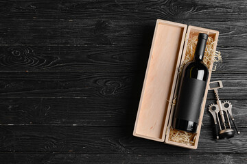 Box with bottle of wine and corkscrew on dark wooden background - obrazy, fototapety, plakaty