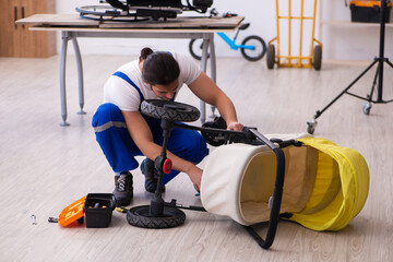 Young male repairer repairing perambulator indoors