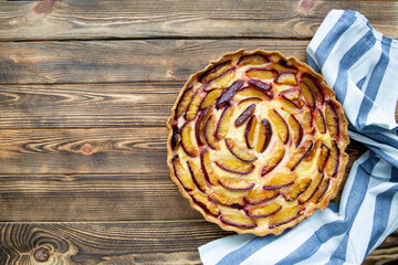 Plum homemade tart on rustic backgorund, top view.