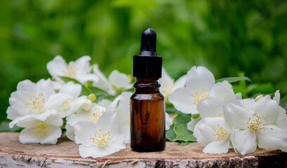 Essential oil and jasmine flowers on a wooden background. Cosmetic procedures.