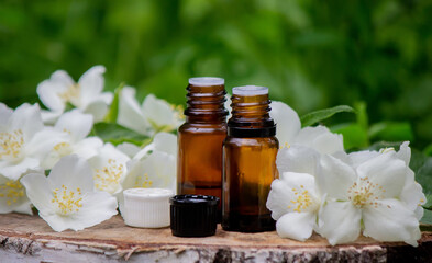 Fototapeta na wymiar Essential oil and jasmine flowers on a wooden background. Cosmetic procedures.