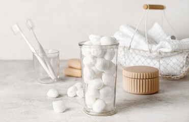 Glass with soft cotton wool on light background