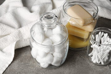 Container with soft cotton wool, soap and swabs on dark background