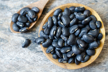Top view of dry organic white bean seed pile in wooden bowl and spoon on grunge background
