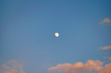 View of the moon in the blue sky surrounded by clouds