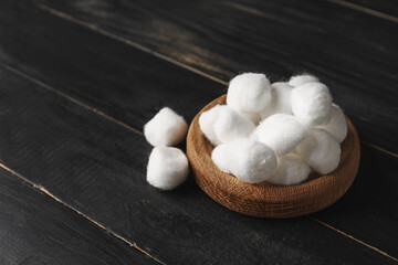 Bowl with soft cotton wool on dark wooden background