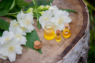 Essential oil and jasmine flowers on a wooden background. Cosmetic procedures.