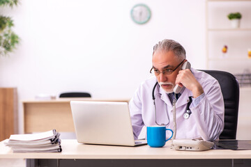 Aged male doctor working in the clinic