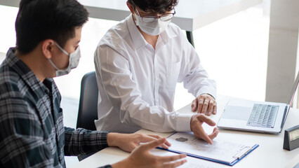 Covid-19 concept two businessmen wearing a mask planning for new project maintaining social distancing during Coronavirus outbreak (COVID-19)