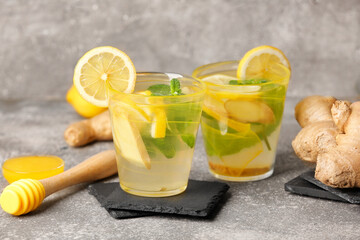 Glasses of cold ginger lemonade on grunge background