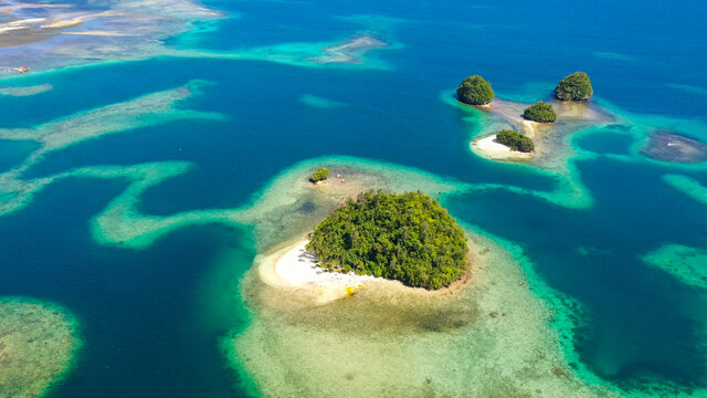 Top view of small tropical island in the blue sea with a coral reef and the beach. Britania Islands, Surigao del Sur, Philippines.