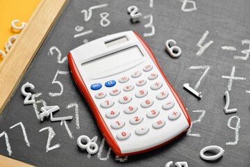 Calculator with chalkboard and figures, closeup