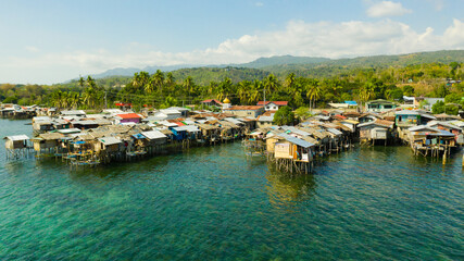 Village of fishermen with houses on the water, with fishing boats. Fishing village with wooden houses on stilts in the sea. Philippines, Mindanao.