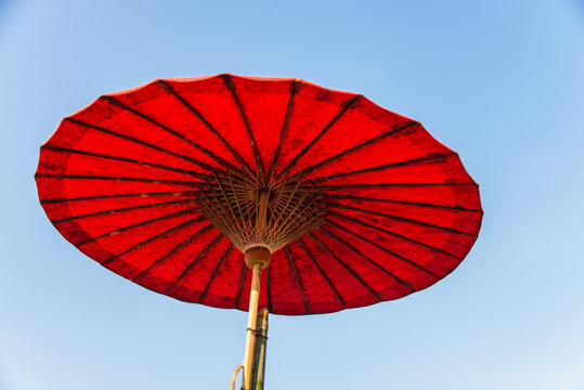 Under red handmade paper umbrella in Thai northern style with clear blue sky