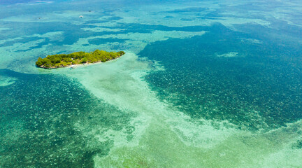Tropical island and blue sea with a coral reef against the sky and clouds. Summer and travel vacation concept. Panglao, Philippines.