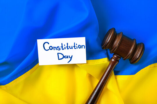 Judge gavel and card with text CONSTITUTION DAY on flag of Ukraine