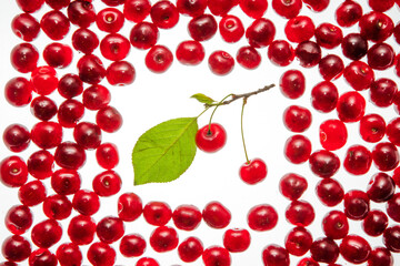 Fresh ripe cherry with green leaves on the white wooden background. Top view, copy space