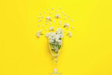 Glass with beautiful lilac flowers on color background