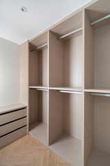 Fototapeta na wymiar New built-in furniture in a small dressing room. Modern and empty storage room with wardrobe, drawers and plenty of space for hangers