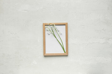 Empty frame and beautiful lily-of-the-valley flowers on light background