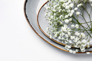 Plates with beautiful gypsophila flowers on white background