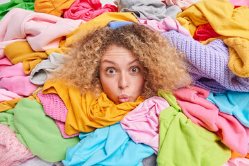Wondered woman keeps lips folded looks surprisingly at camera collects personal stuff overloaded...