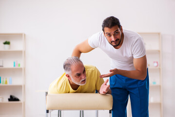 Obraz premium Old male patient visiting young male doctor chiropractor