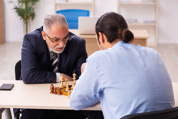Two businessmen playing chess in the office