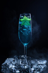 Cold blue cocktail with a star fruit garish on black background.