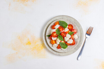 Delicious Italian caprese salad with sliced red and orange cherry tomatoes and mozzarela balls.