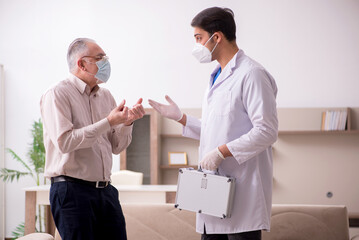 Obraz premium Young male doctor visiting old patient in vaccination concept