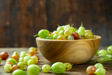 Ripe gooseberry in a wooden plate, place for text