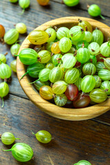 Ripe gooseberry in a wood plate, place for text, top view