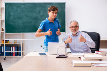 Old male teacher and schoolboy in the classroom