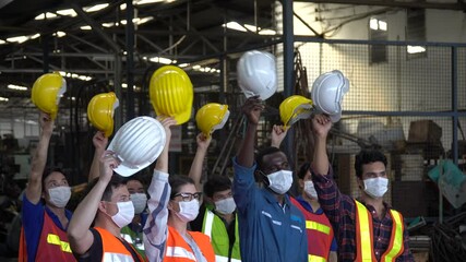 group of factory workers wear protective face mask excited and celebrating holding headhat rising up in meeting at industrial factory protect for pollution and coronavirus  or covid 19 pandemic