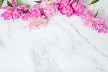 Template for a romantic greeting card with pink peonies on a white marble table. Blossoming flowers on a white background.