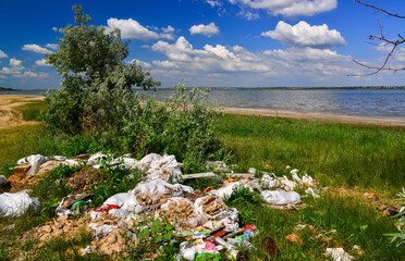 Pollution of nature, a pile of plastic garbage on the shore of a reservoir, ecological disaster,...