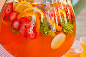 Fototapeta na wymiar Fruit punch in a large glass bowl. Drink with a variety of fruits close up. Orange alcoholic cocktail.