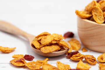 The wooden bowl of caramel cornflakes with raisins on white background for healthy eating and breakfast concept