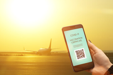 vaccination qr code,vaccine certificate and digital green passport of covid-19 for travel,tourism hand with smartphone and airplane on the runway