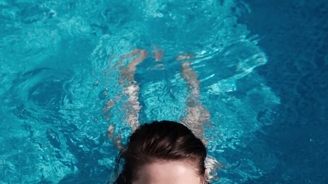 Close up of an young woman swimming and having relax in an outdoor above ground pool.